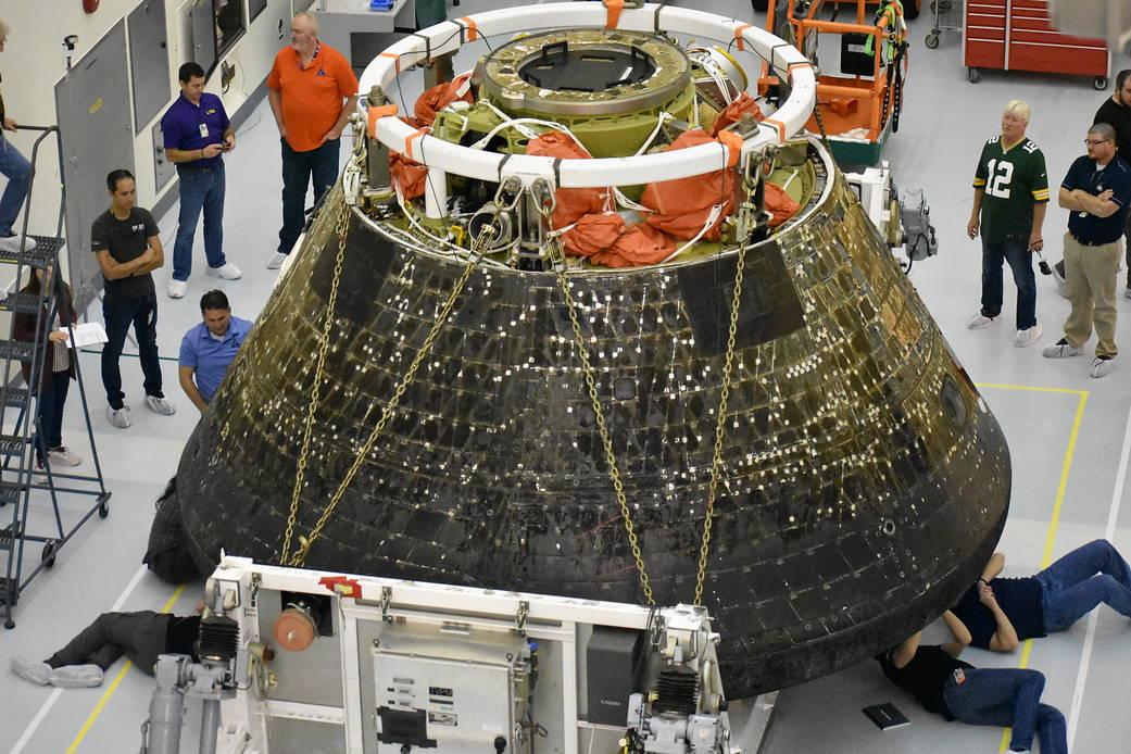 Orion spacecraft under inspection by engineers and technicians.